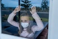 COVID-19 Quarantine. Sad little girl looking through the window feeling lonely during lockdown Royalty Free Stock Photo