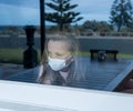 COVID-19 Quarantine. Sad little girl looking through the window feeling lonely during lockdown Royalty Free Stock Photo