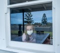 COVID-19 Quarantine. Sad little girl looking through the window feeling lonely during lockdown Royalty Free Stock Photo