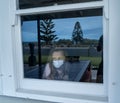 COVID-19 Quarantine. Sad little girl looking through the window feeling lonely during lockdown Royalty Free Stock Photo