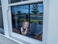 COVID-19 Quarantine. Sad little girl looking through the window feeling lonely during lockdown Royalty Free Stock Photo