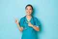 Covid-19, social distancing and coronavirus pandemic concept. Cheerful smiling asian female nurse, doctor in scrubs Royalty Free Stock Photo