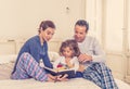 COVID-19 Stay Home. Happy family, parents and little cute daughter reading a book together Royalty Free Stock Photo