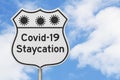 Covid-19 Staycation highway road sign with virus symbols