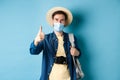 Covid-19 and summer holidays concept. Cheerful tourist in straw hat and medical mask praise and recommend good vacation