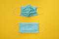 COVID-19 two disposable surgical face masks on yellow background