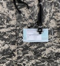 Covid 19 vaccination record card, personal facemask and stethoscope on military uniform