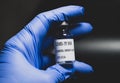 covid 19 vaccine bottle is being held by a hand with a blue latex glove Royalty Free Stock Photo