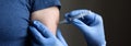 COVID-19 vaccine shot, doctor in gloves holds syringe and makes jab to woman patient