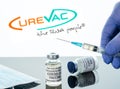 Covid-19 vaccine in vial with syringe reflected against Curevac logo on white background