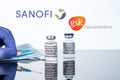 Covid-19 vaccine in vial with syringe reflected against white Sanofi GSK background