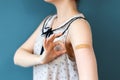 The covid-19 vaccine. A woman in a blouse shows her hand with a band-aid and makes an OK gesture. Dark blue background Royalty Free Stock Photo