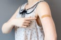 The covid-19 vaccine. A woman in a blouse shows her hand with a band-aid and point it with index finger. Dark blue Royalty Free Stock Photo