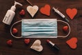 Covid valentine`s day concept. face mask with red and white hearts on wooden background. hand sanitizer and lipstick for the new Royalty Free Stock Photo