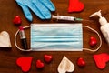 Covid valentine`s day hygiene concept. face mask with red hearts on wooden background. top view of hand sanitizer and lipstick an Royalty Free Stock Photo