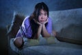 Covid-19 virus home lockdown - dramatic portrait of young beautiful depressed and scared Asian Chinese woman lying sad and
