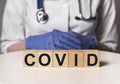 Covid word, inscription on wooden dices in doctor hands