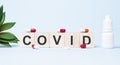 COVID word made with building blocks. A row of wooden cubes with a word written in black font is located on white background