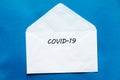 COVID - 19 written on white envelope on blue background.