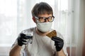 COVID-19. Young caucasian man in glasses, white mask and black gloves with a slice of bread and a cup of water in his hands. Royalty Free Stock Photo