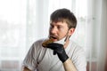 COVID-19. Young caucasian man in white mask and black gloves with a slice of bread in his hands in the kitchen during a pandemic.