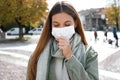 COVID-19 Young woman coughs with surgical mask during coronavirus pandemic disease in city street. Girl having symptoms like Royalty Free Stock Photo