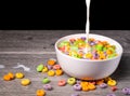 Cow milk drooping into a bowl with colorful cereal rings Royalty Free Stock Photo