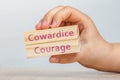 Cowardice and Courage. A hand holds two wooden cubes with the inscriptions COWARDICE and COURAGE close-up For insertion