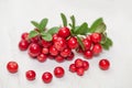 Cowberry with green leaves on white wooden board