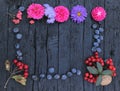 Cowberry with leaves, black raisins, flowers, and walnut as a frame on wooden background