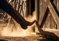 Cowboy boot kicking open farm barn door with dust cloud at sunset Royalty Free Stock Photo