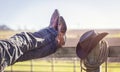 Cowboy boots and hat with feet up on fence resting with legs crossed Royalty Free Stock Photo