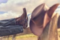 Cowboy boots and hat with feet up on fence resting with legs crossed