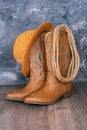 Cowboy boots, hat and rope against a gray wall. Adventure and travel concept Royalty Free Stock Photo