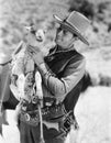 Cowboy carrying a lamb and smiling Royalty Free Stock Photo