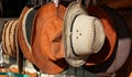 Cowboy Christmas. American West traditional pure leather hats displayed outdoors for sale in sunlight. They are hanging next to