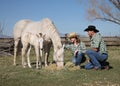 Cowboy couple with white horse family grassy field