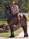 Cowboy, farm and relax on horse in outdoor, wellness and equestrian sport on western ranch. Strong, stallion and jockey