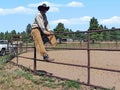 Cowboy on a fence on a ranch looking
