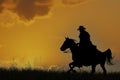 Cowboy galloping across hill against dawn sky Royalty Free Stock Photo