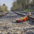 Cowboy hat and an abandoned guitar on the rails of the train track on a sunny day
