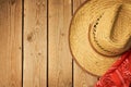 Cowboy hat on wooden vintage table with red bandanna for party invitation.