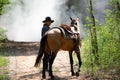 Cowboy on his horse walking through dust in the forest Royalty Free Stock Photo