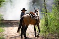 Cowboy on his horse walking through dust in the forest