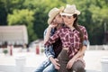 Cowboy kissing his sensual girlfriend while sitting on fence at ranch