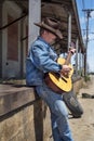 Cowboy playing acoustic guitar wearing jeans outdoors Royalty Free Stock Photo