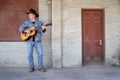 Cowboy playing acoustic guitar wearing jeans outdoors Royalty Free Stock Photo