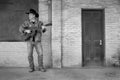 Cowboy playing acoustic guitar wearing jeans outdoors Royalty Free Stock Photo