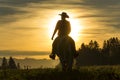Cowboy riding across grassland with mountains in the background Royalty Free Stock Photo