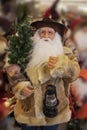 Cowboy Santa Claus in shearling coat with saddle and lantern and Christmas tree - selective focus - blurred background Royalty Free Stock Photo